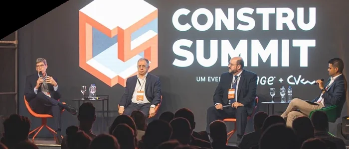 Palestra durante o Construsummit, com homens no palco e plateia lotada